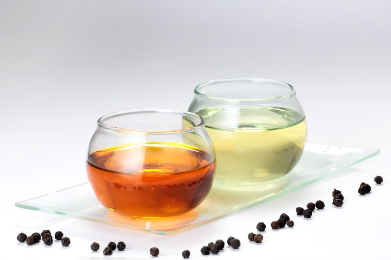 Muestra de los dos principales aceites derivados de la palma de aceite: Aceite de Palma Crudo (AP) y Aceite de Palmiste (APL), ilustrando la diferencia en color y composición.