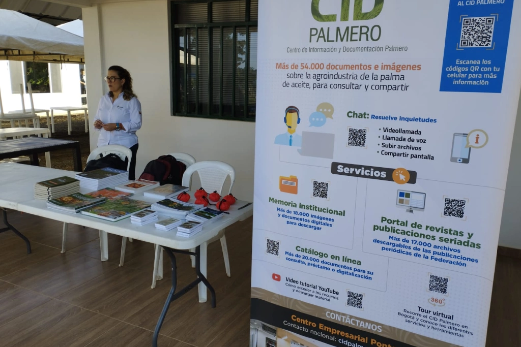 Stand de promoción del Centro de Información y Documentación Palmero (CID PALMERO), mostrando material impreso y una pancarta que describe sus más de 54.000 documentos y servicios para la agroindustria de la palma de aceite.