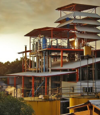 Estructura de una planta, en medio de árboles, con el atardecer a un lado.