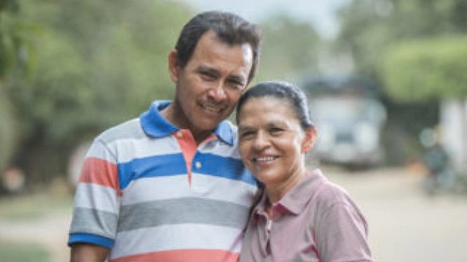 Retrato de una pareja de mediana edad sonriendo al aire libre.