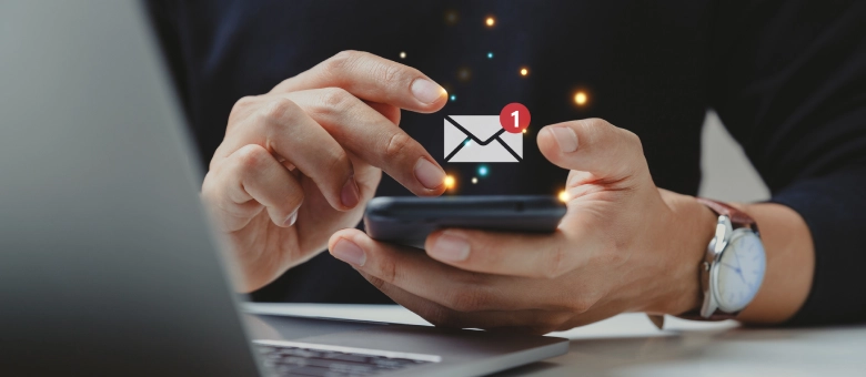 Hombre revisando el celular, con una notificación de correo electrónico flotando sobre la pantalla