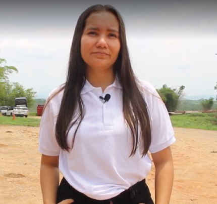 Mujer joven con cabello oscuro, vistiendo una camisa polo blanca en un camino de tierra.