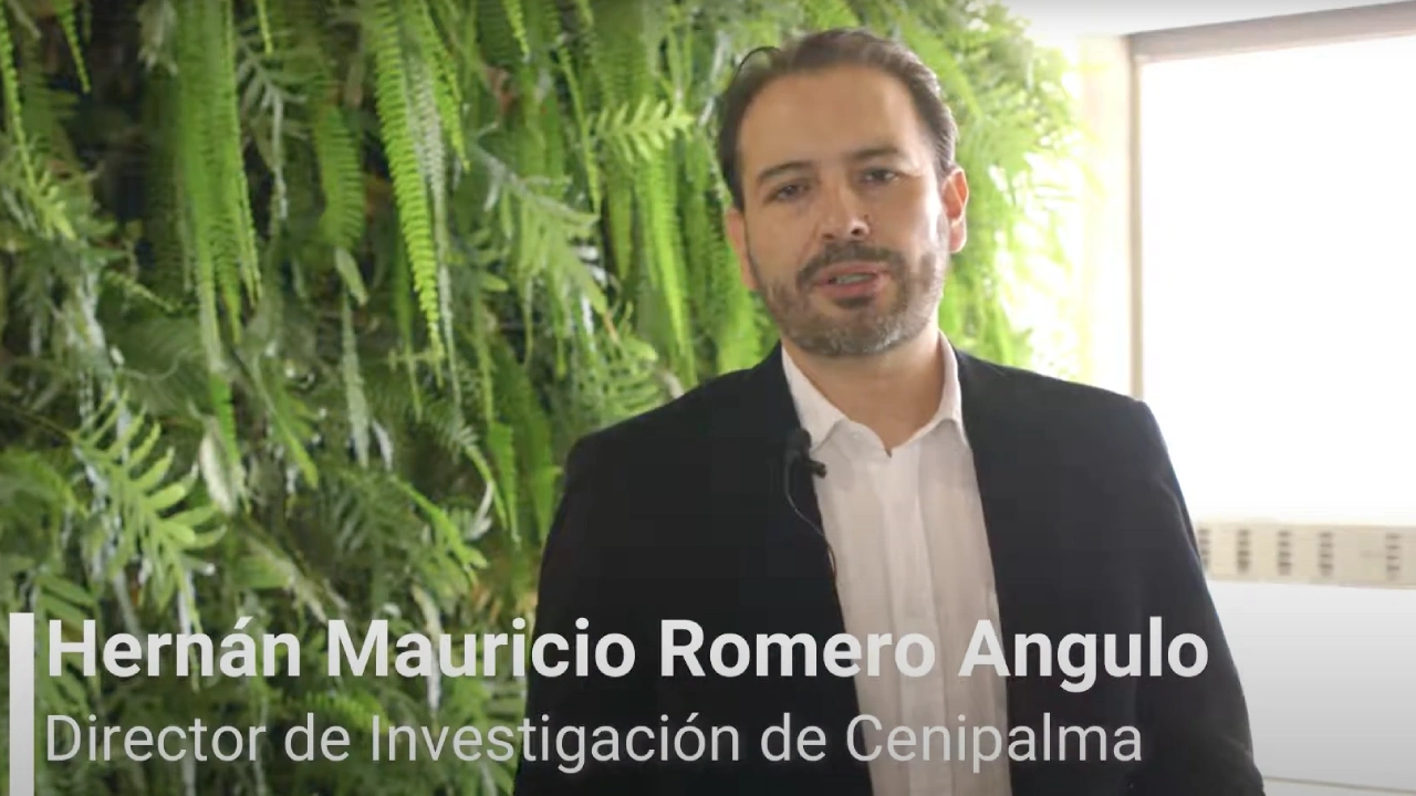 Hernán Mauricio Romero Angulo, Director de Investigación de Cenipalma, de pie frente a un muro verde con plantas.