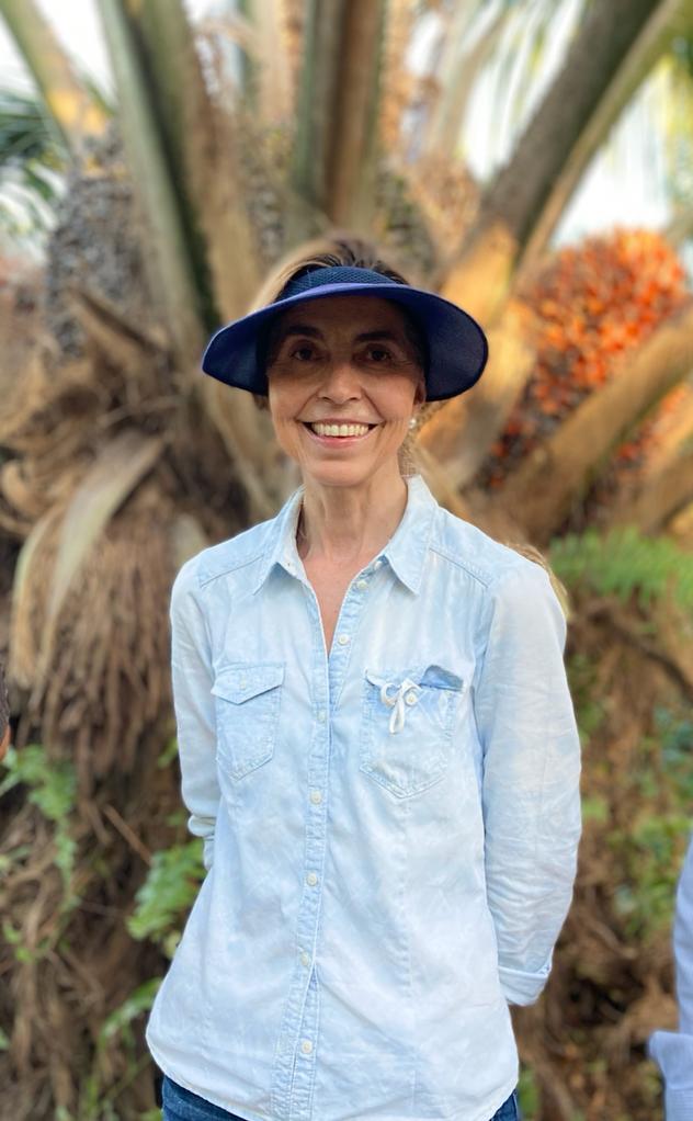 mujer sonriente con una visera azul y camisa de mezclilla azul claro