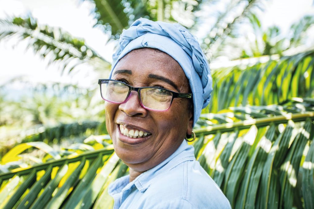 Retrato de una trabajadora o agricultora de palma de aceite sonriendo, destacando la presencia femenina en el sector agrícola.