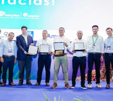 Ocho hombres posando en un escenario mientras sostienen premio de sostenibilidad